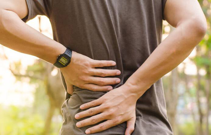 Man holding his back due to back pain, a symptom of testicular cancer