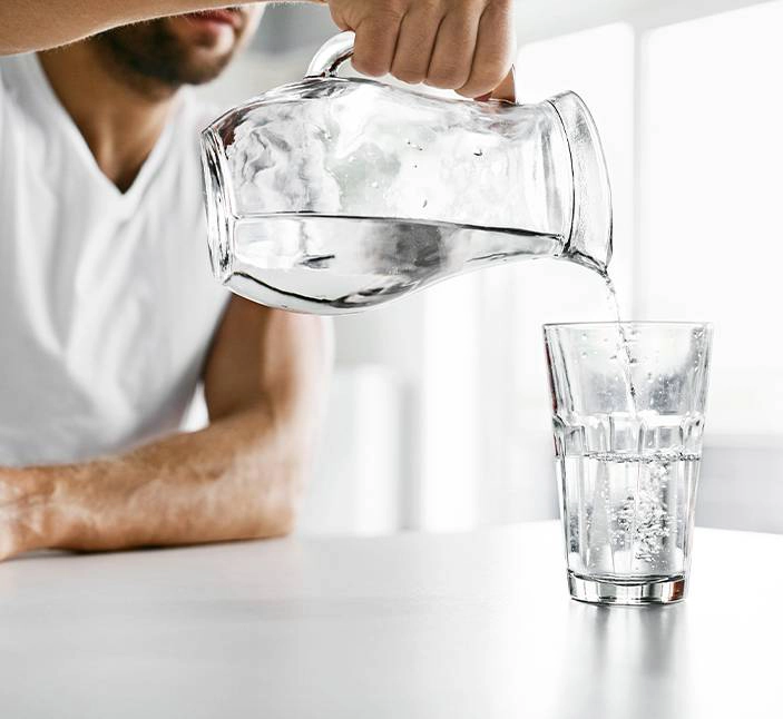 Man pouring a glass of water as part of a prostatitis lifestyle, avoiding alcohol